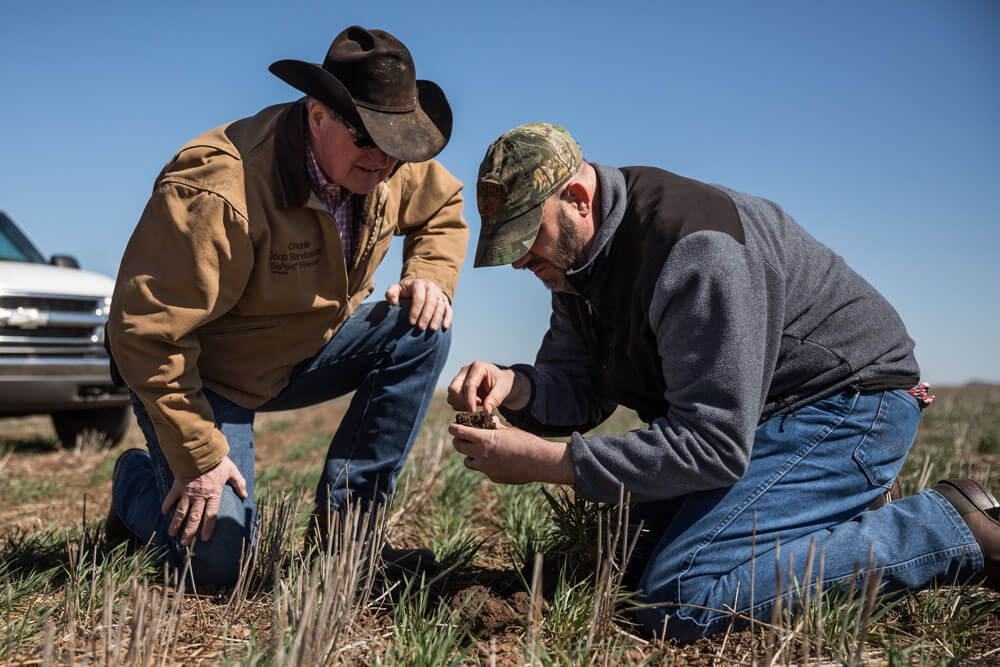 Jim Johnson inspects soil with a producer