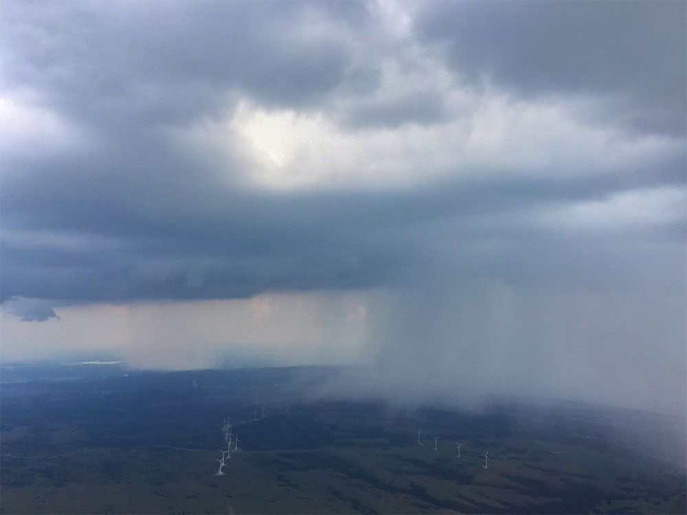 Rainstorm over a field of windmills, photographed from the window of an airplane.