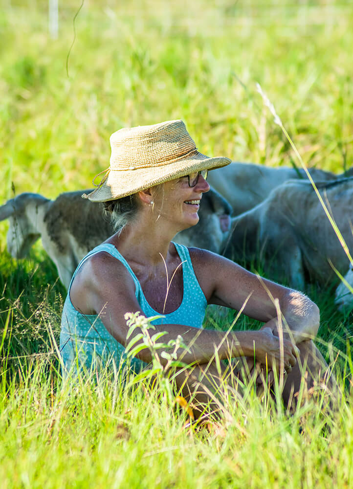 Christine sitting in pasture with sheep.