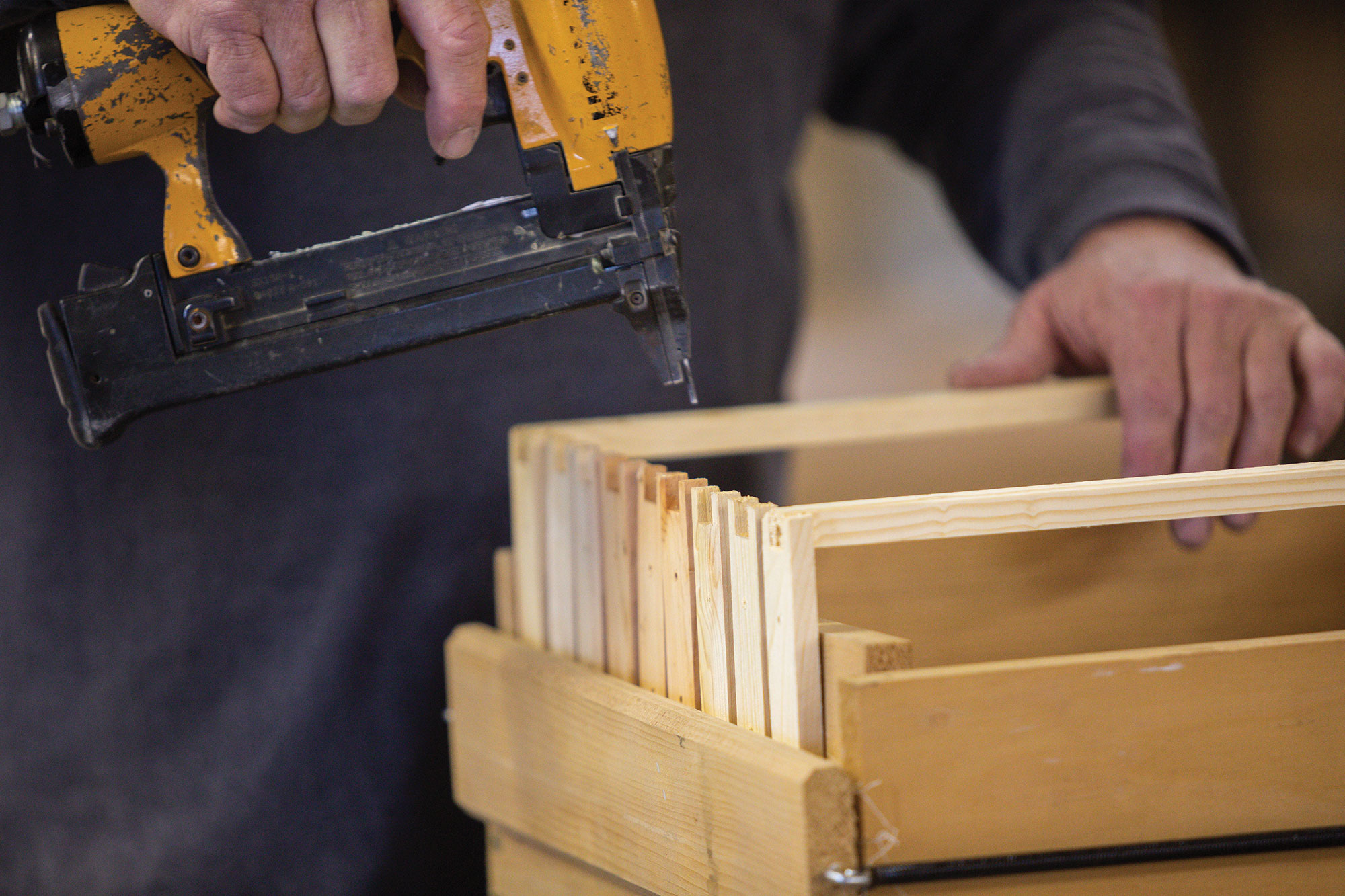 Attaching pieces to the beehive with a nailgun.