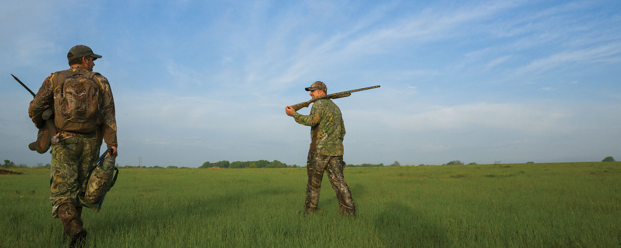Hunters walking in field with guns