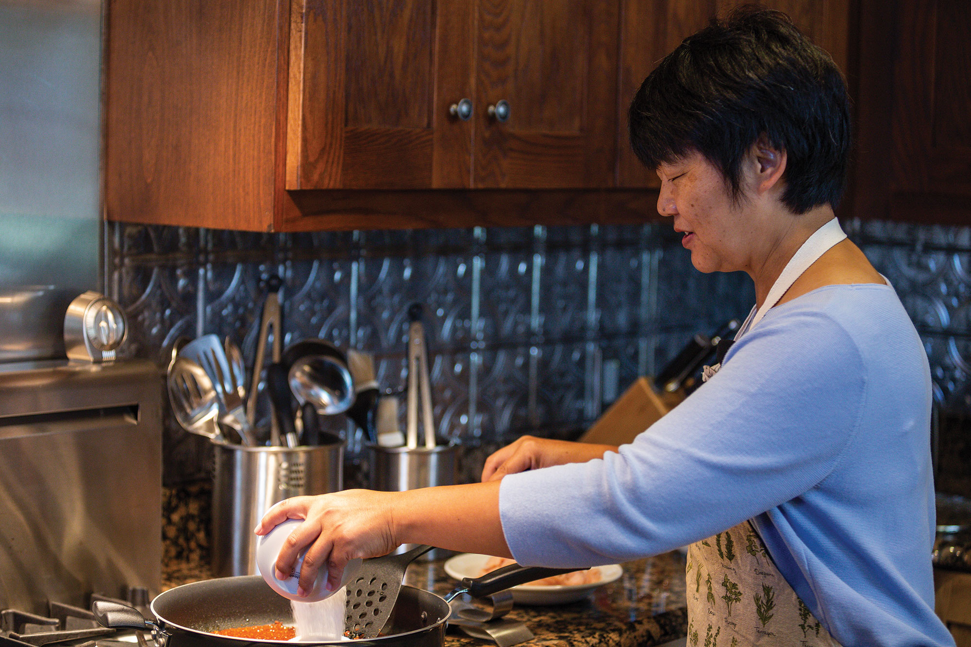 Yuhong Tang adds ingredients to the pan