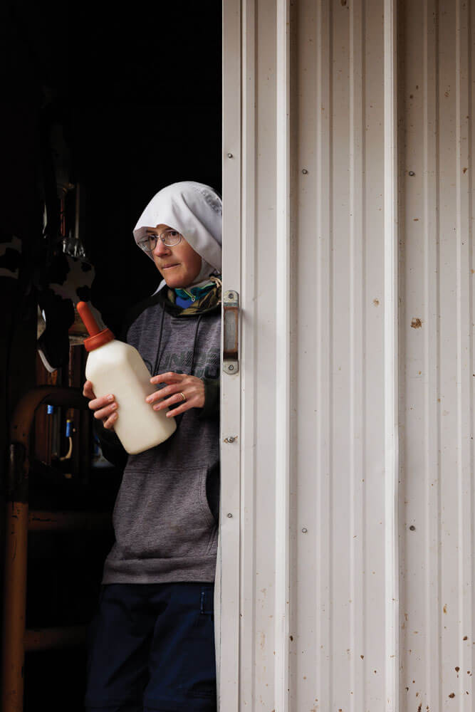 Sister Gertrude prepares to bottle feed calf.