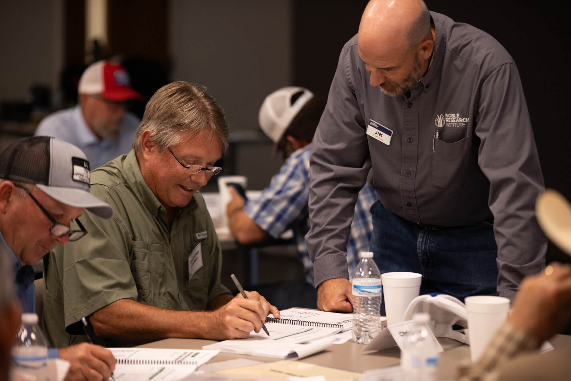 Noble Research Institute course facilitator Jim Johnson visits with rancher Christopher Landherr as he completes a workbook page during the Essentials of Regenerative Ranching course at Stephenville, Texas.
