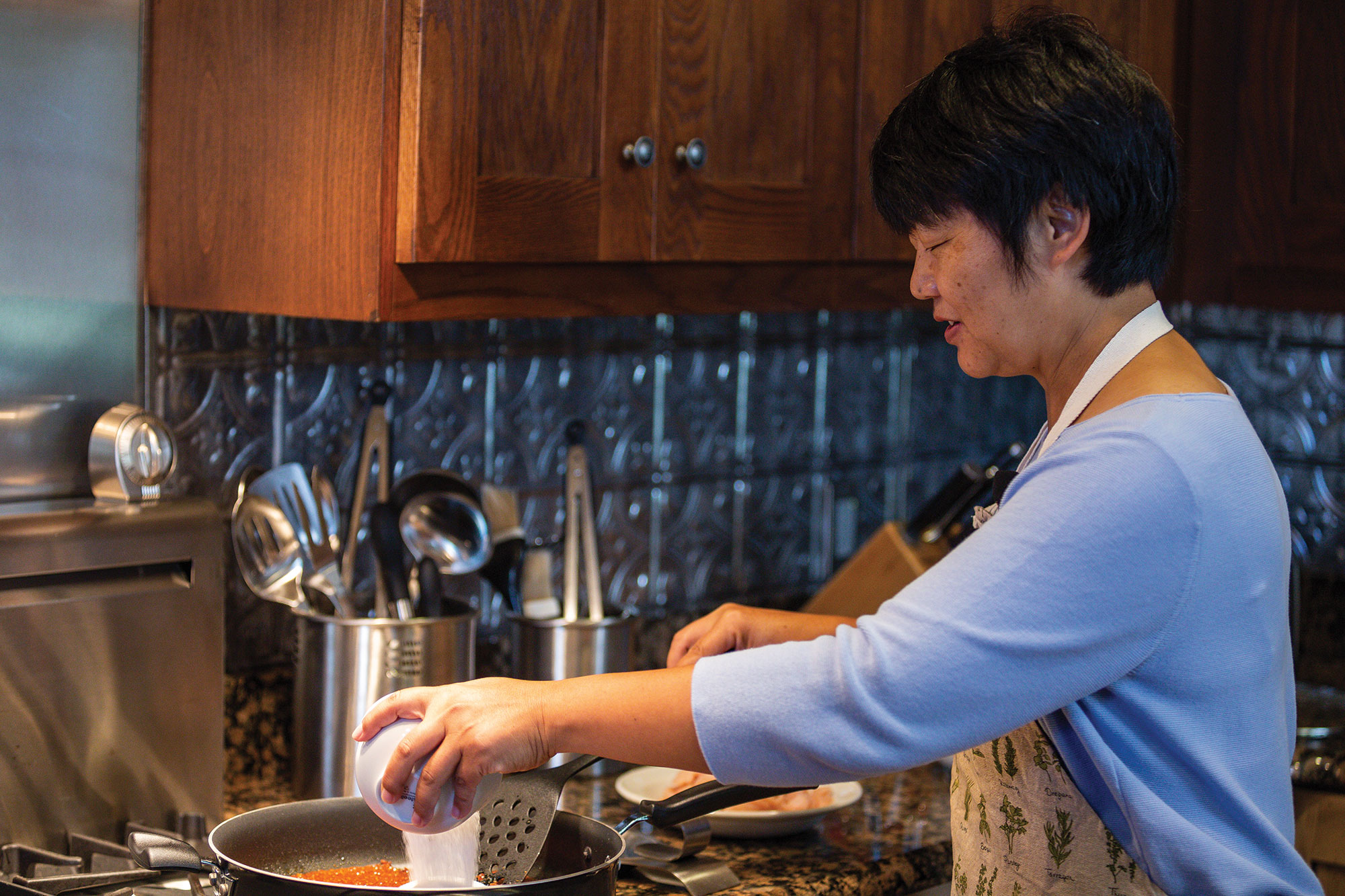 Yuhong Tang adds ingredients to the pan Yuhong Tang adds ingredients to the pan