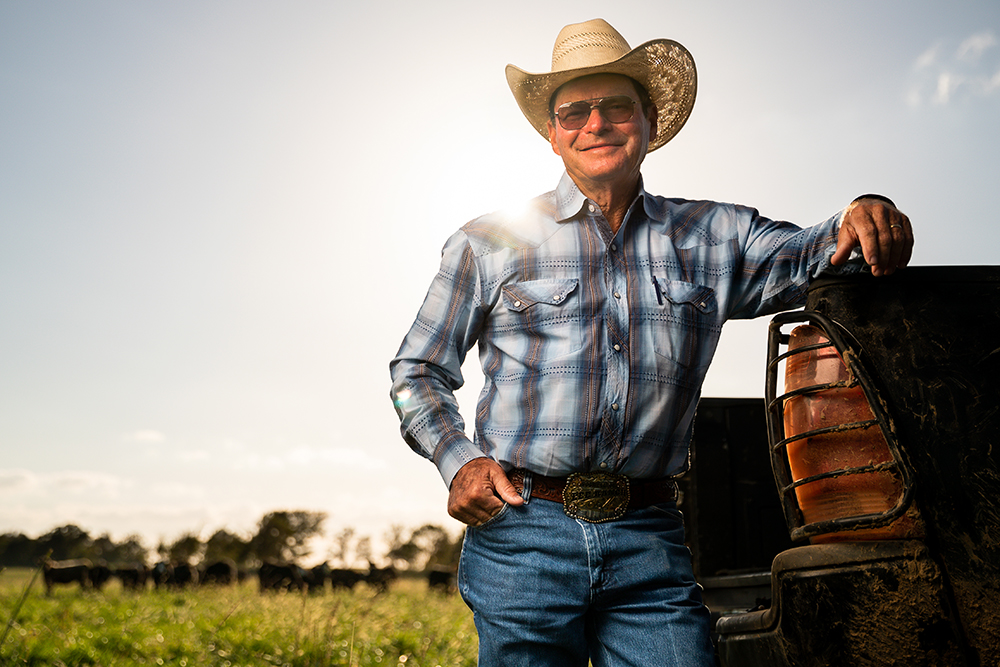 Rancher standing in field next to truck